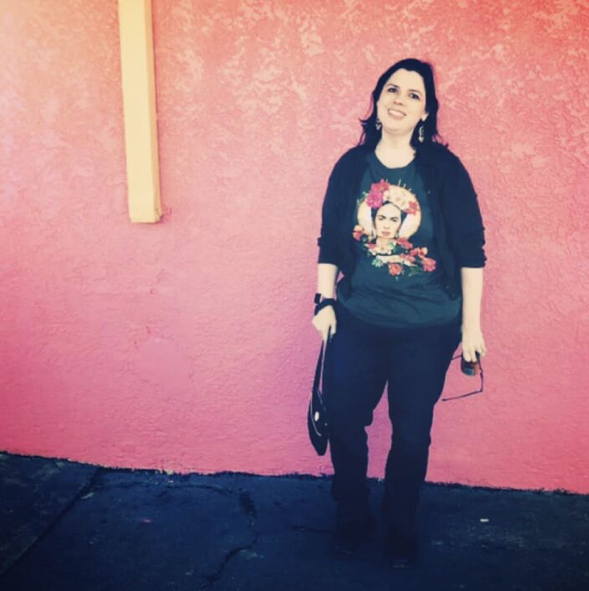 Melanie Sage standing against a bright pink wall
