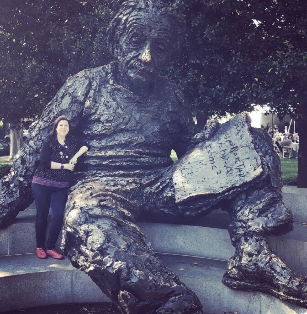 Melanie Sage seated beside a statue of Albert Einstein